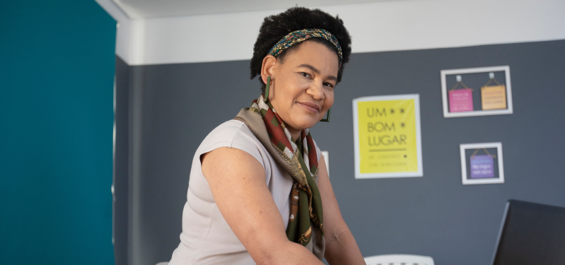 Mulher negra, com lenço no pescoço, posando para foto sorrindo. Foto: Adobe Stock