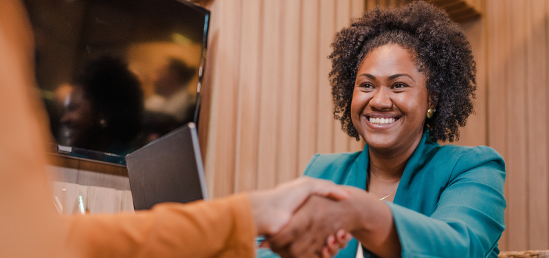 Mulher negra de blazer verde sorrindo. Foto: Adobe Stock