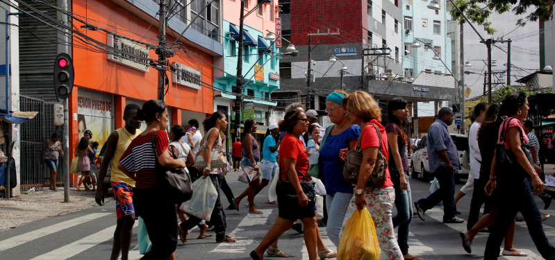 Pessoas caminham em região comercial. Foto: Adobe Stock