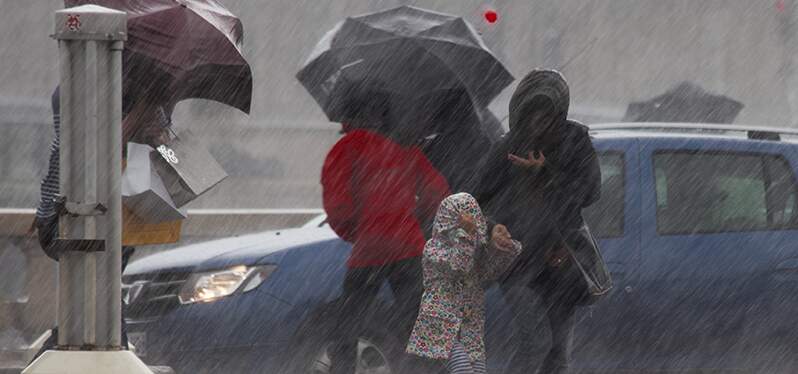 Pessoal andando na rua durante chuva. Foto: Adobe Stock