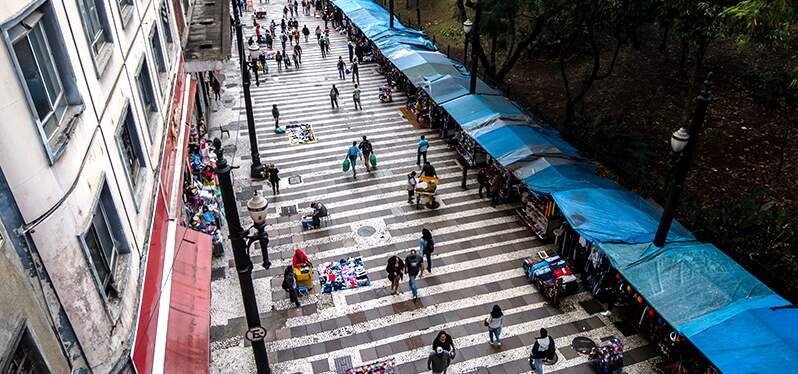 Brasil reduz índice de pobreza e extrema pobreza. Pessoas andando em rua comercial movimentada. Foto: Adobe Stock